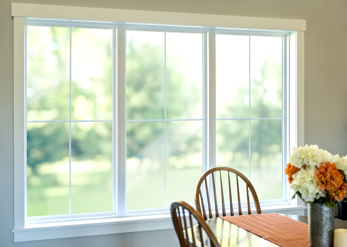Bright dining area with large white windows and flowers.